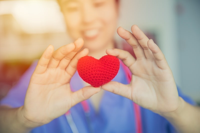 Nurse holding a red heart symbolizing compassion and care in healthcare