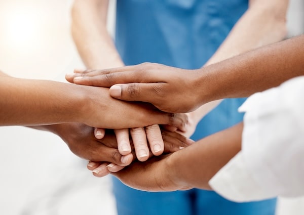 Hands stacked in teamwork to represent CNA collaboration and support