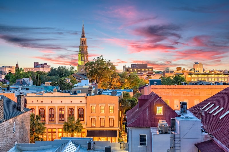 Sunset view of Charleston, South Carolina with colorful buildings and church steeples.