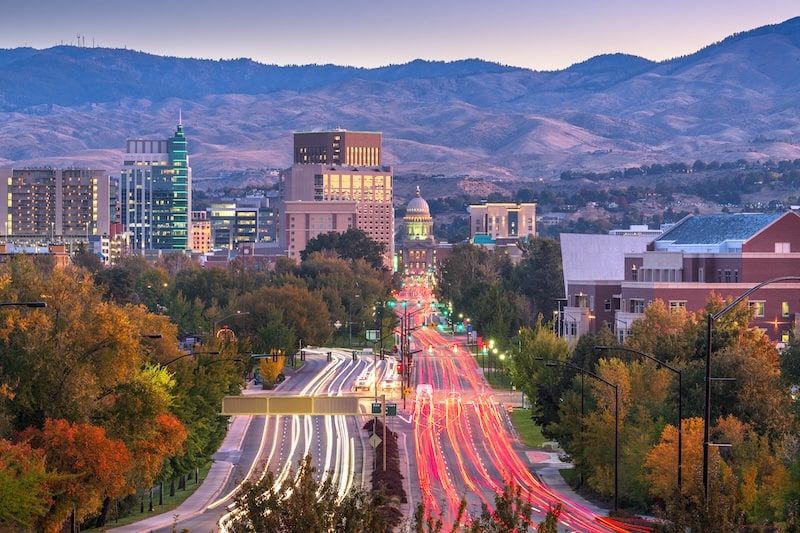 Downtown Boise, Idaho at twilight with city lights and mountains in the background.