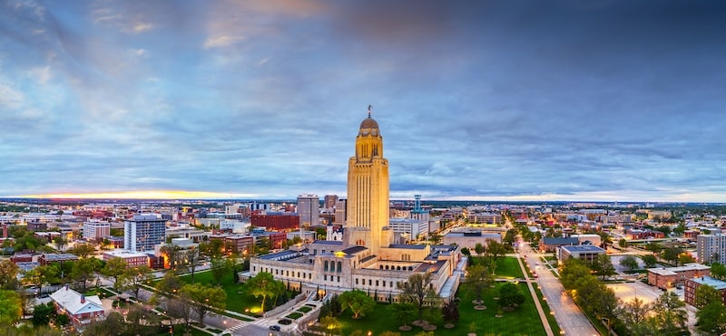 Panoramic view of Lincoln, Nebraska skyline featuring the state capitol building at sunrise.