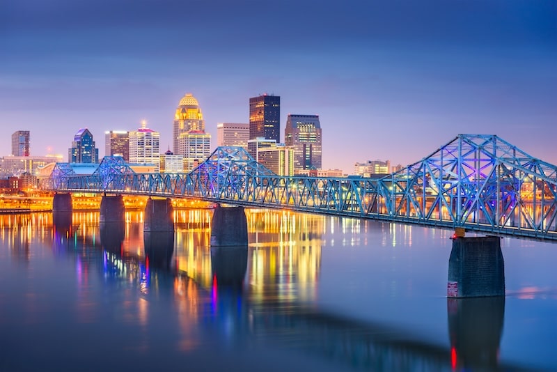 Night view of the downtown Louisville skyline and illuminated bridge reflecting on the river