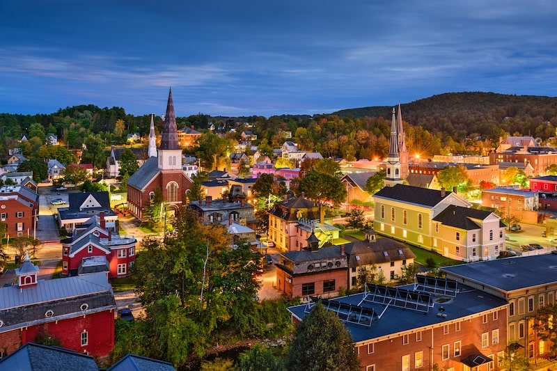 Nighttime view of downtown Montpelier, Vermont with historic churches and fall foliage.