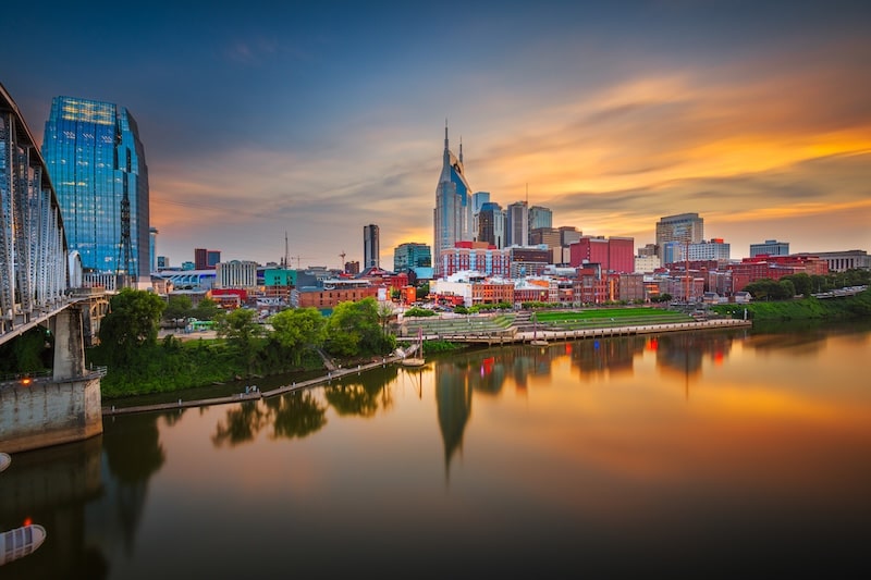Downtown Nashville, Tennessee skyline at sunset with reflections in the Cumberland River.