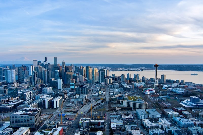 Aerial view of Seattle skyline with Space Needle and Mount Rainier in the background at sunset.