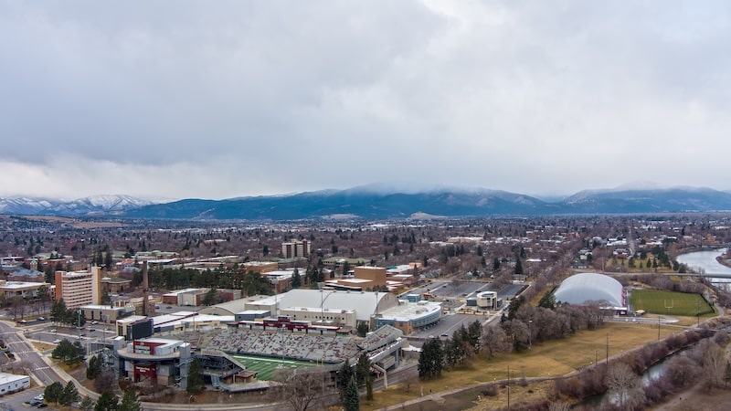 Aerial view of Washington-Grizzly Stadium and surrounding campus in Missoula, Montana with mountains in the distance.